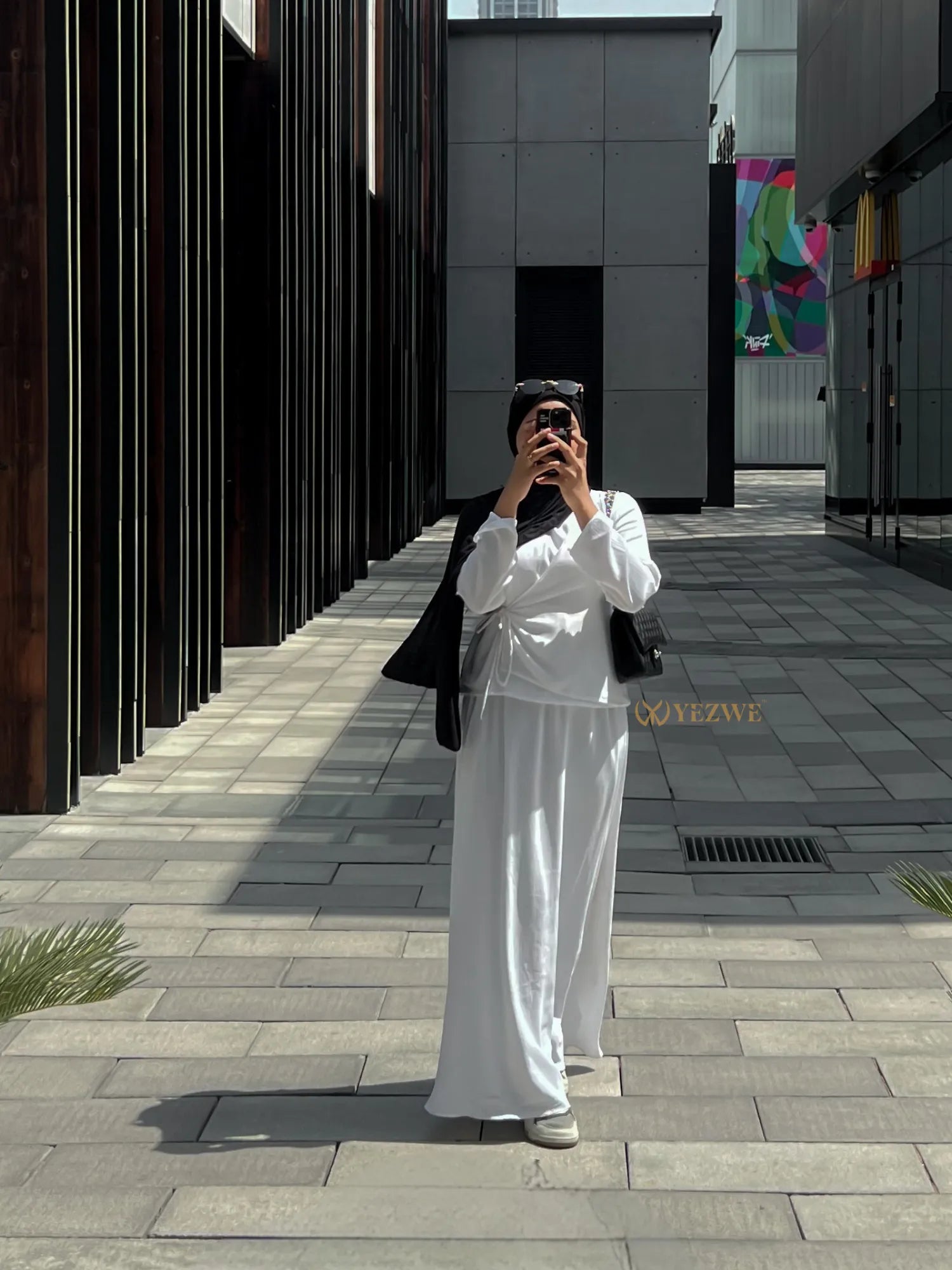 Woman wearing white YEZWE Co-Ord set with long skirt and top in urban outdoor setting