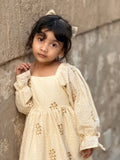 little girl wearing cream embroidered ethnic dress standing near wall close up soft portrait looking at camera