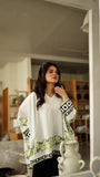 woman wearing cream printed modest top with black skirt looking in mirror indoors with aesthetic home background