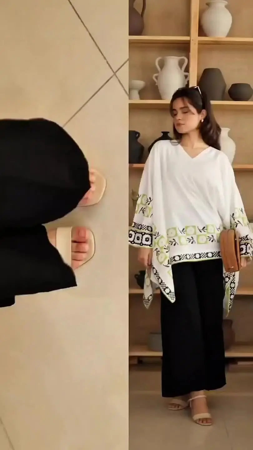 woman wearing cream printed modest top with black pants standing indoors in aesthetic lifestyle setting