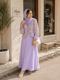 Woman wearing a lavender floral modest maxi dress with matching hijab standing outside a café with a white handbag.