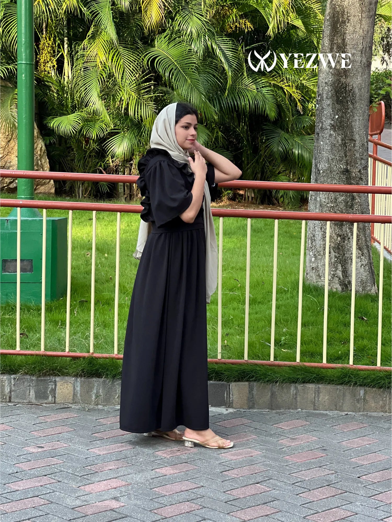 YEZWE modest black maxi dress worn by woman outdoors with green foliage background