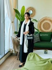Yezwe modest black maxi dress styled with a white scarf and chic handbag in a bright indoor setting