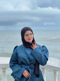 Woman wearing YEZWE Modest Co-Ord Set in teal with long sleeves and floral belt detail by the sea
