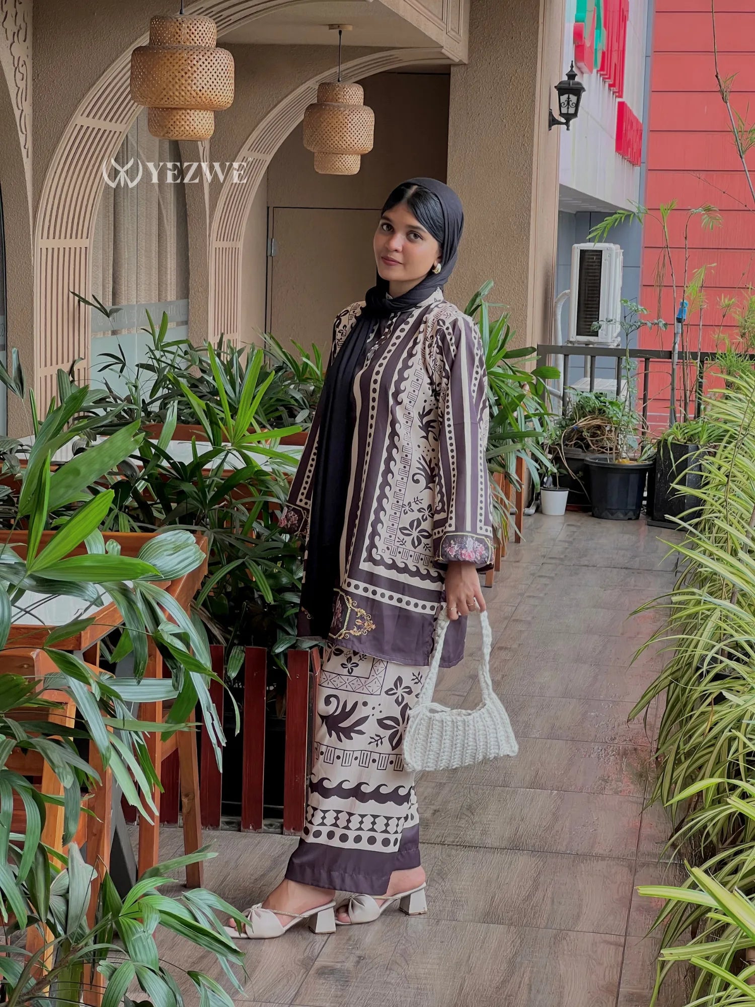 Woman wearing YEZWE modest ethnic co-ord set with intricate patterns standing on a garden walkway