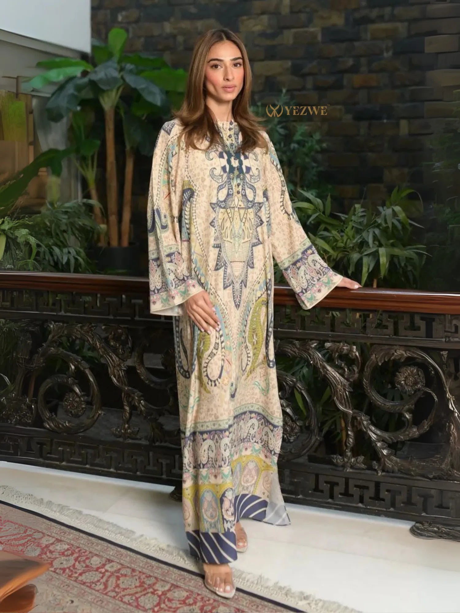 Yezwe Modest Kaftan Dress tunic in neutral paisley print worn by model standing indoors by decorative railing