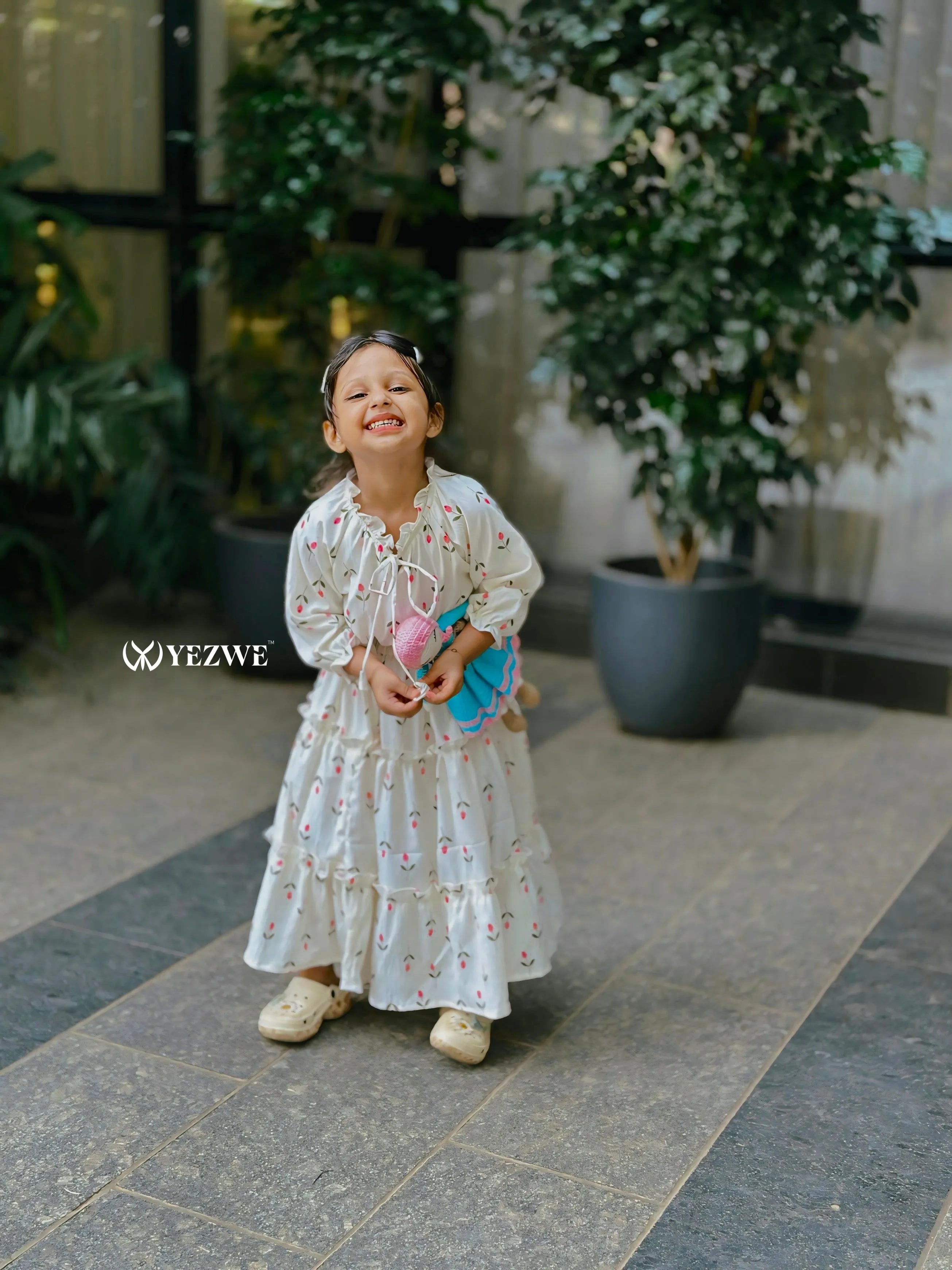 Girl in a Yezwe modest Korean oneset outfit with floral design, smiling in a green setting
