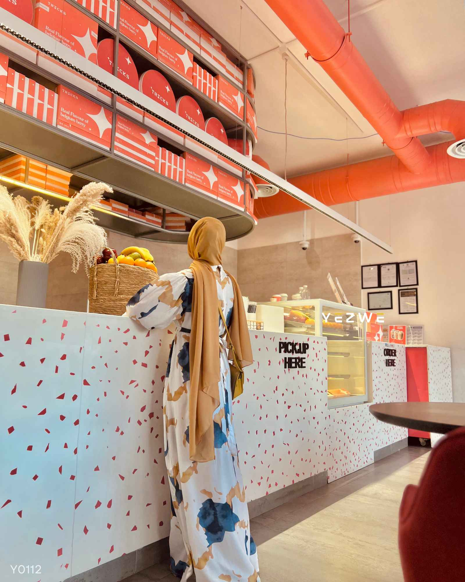 Woman wearing a modest marble maxi dress in a stylish café environment