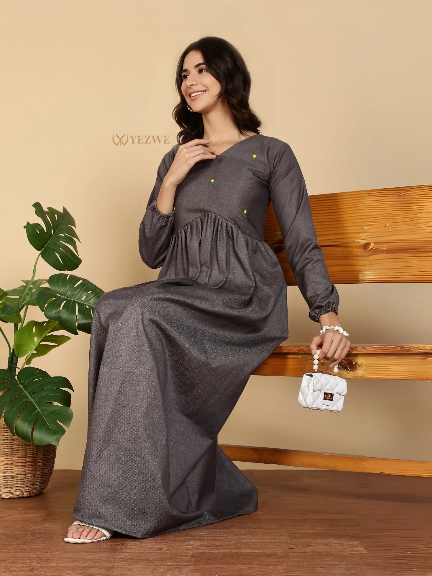 Yezwe Modest Maxi Dress gray long sleeve gathered waist model seated on wooden bench holding white handbag