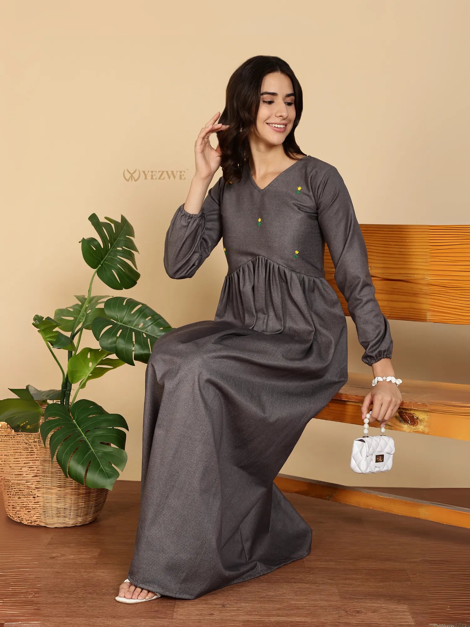 Yezwe Modest Maxi Dress gray long sleeve gathered waist V neck model seated on bench holding white handbag