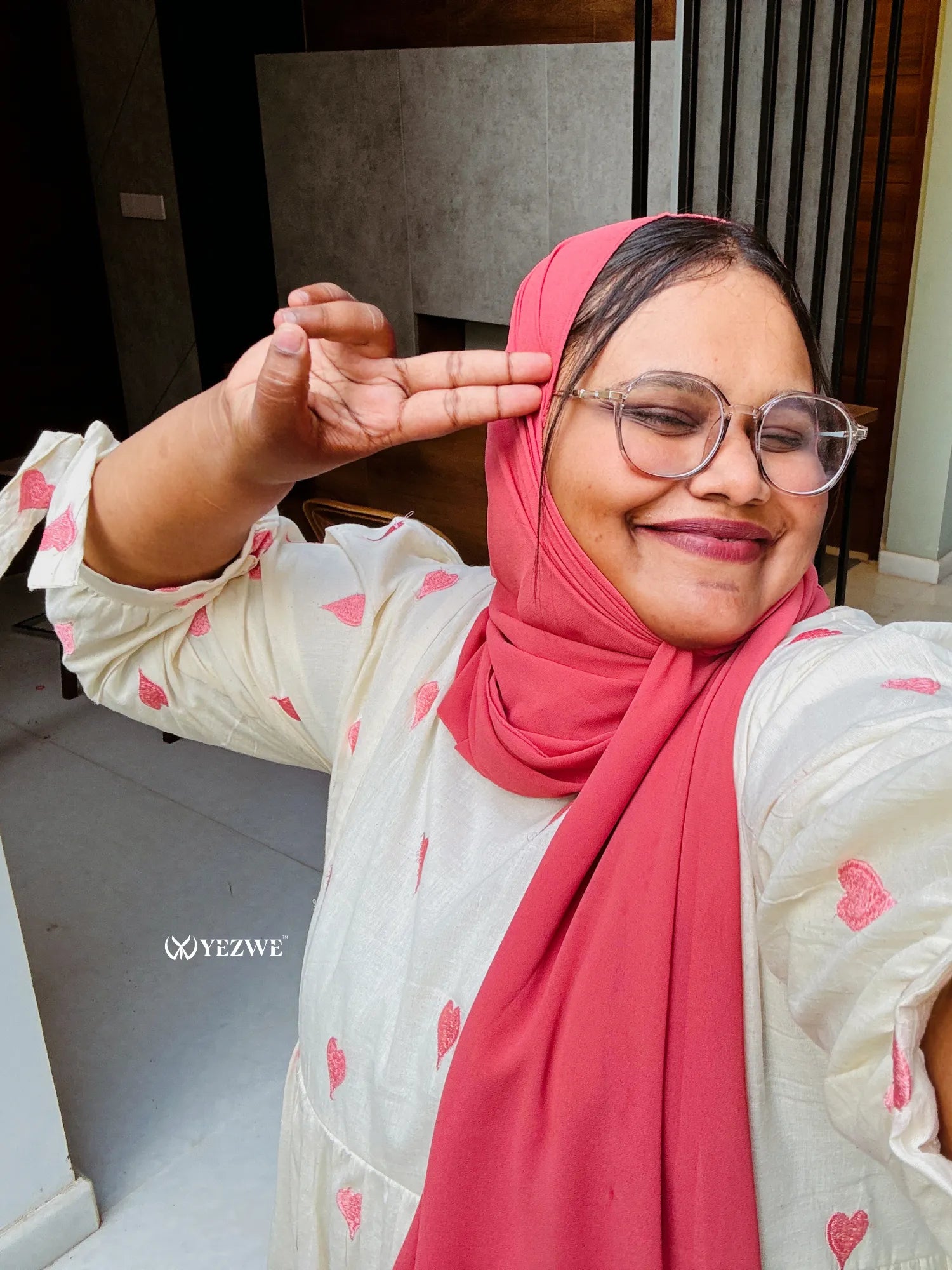 Happy woman wearing a modest pastel pink maxi dress and a matching hijab for a stylish look