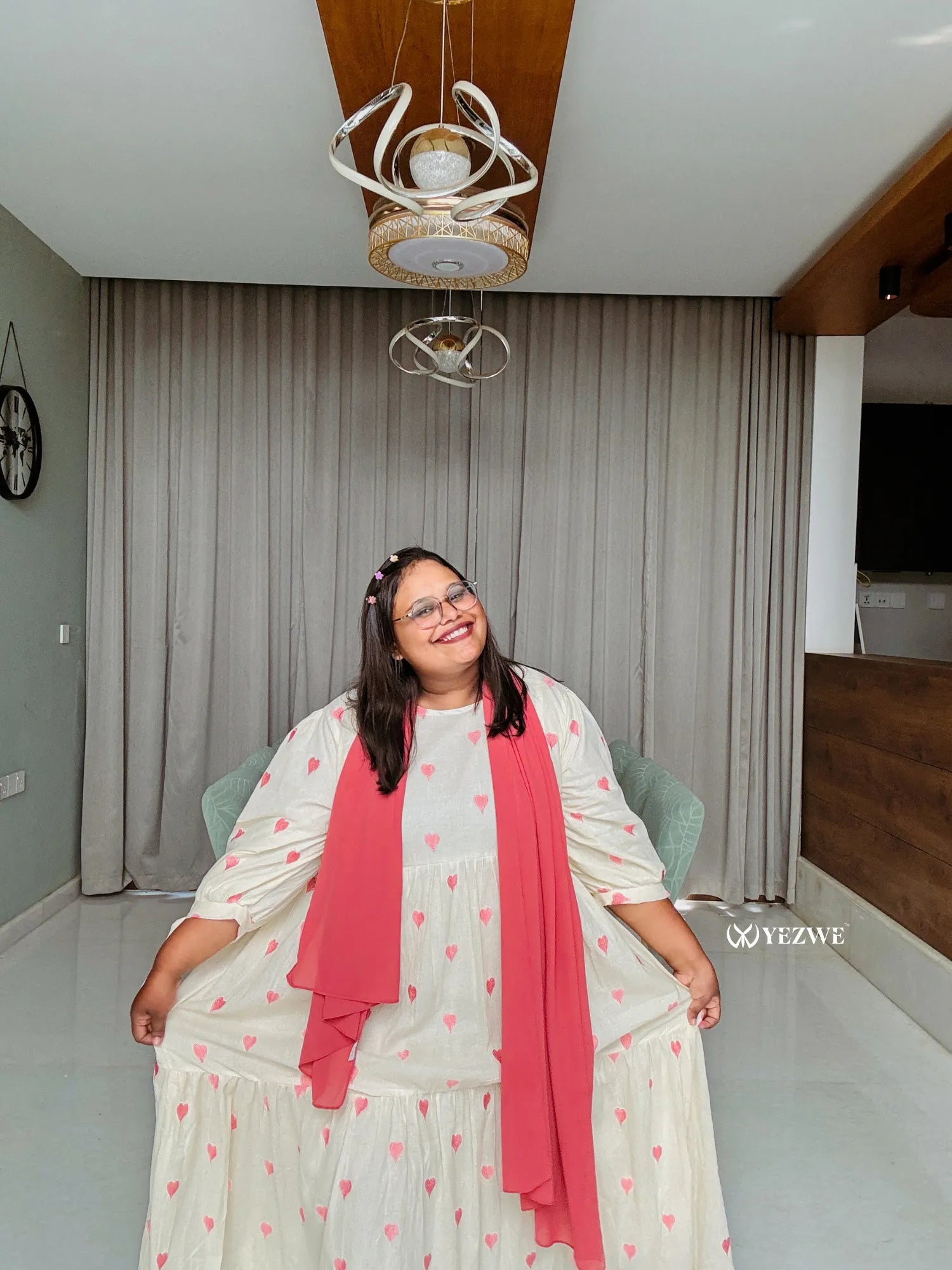 Model wearing a modest pastel pink maxi dress with heart patterns and a matching shawl indoors