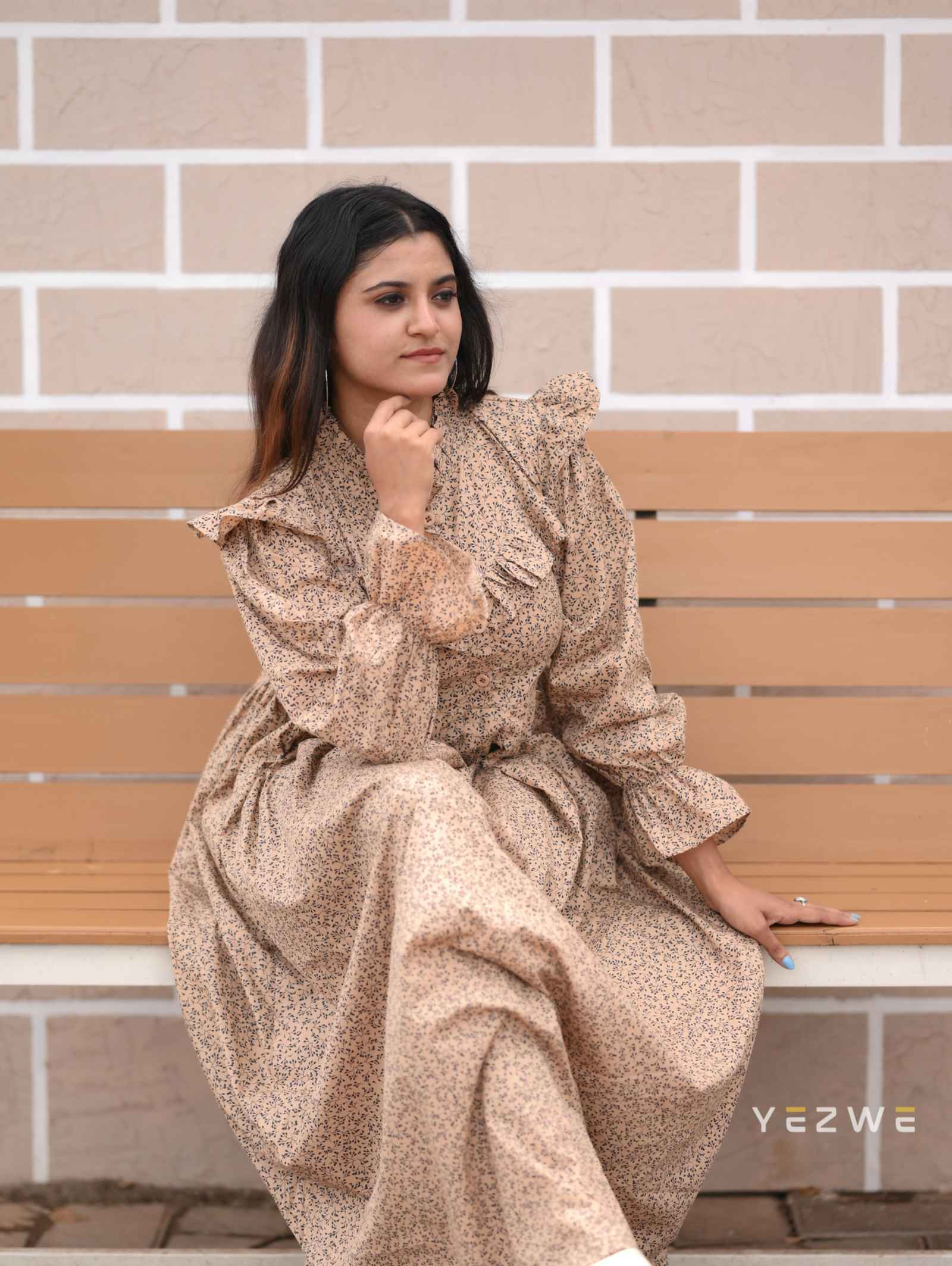 Yezwe modest print maxi dress in beige with ruffled sleeves, styled elegantly on a model sitting on a bench