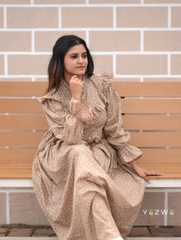 Yezwe modest print maxi dress in beige with ruffled sleeves, styled elegantly on a model sitting on a bench