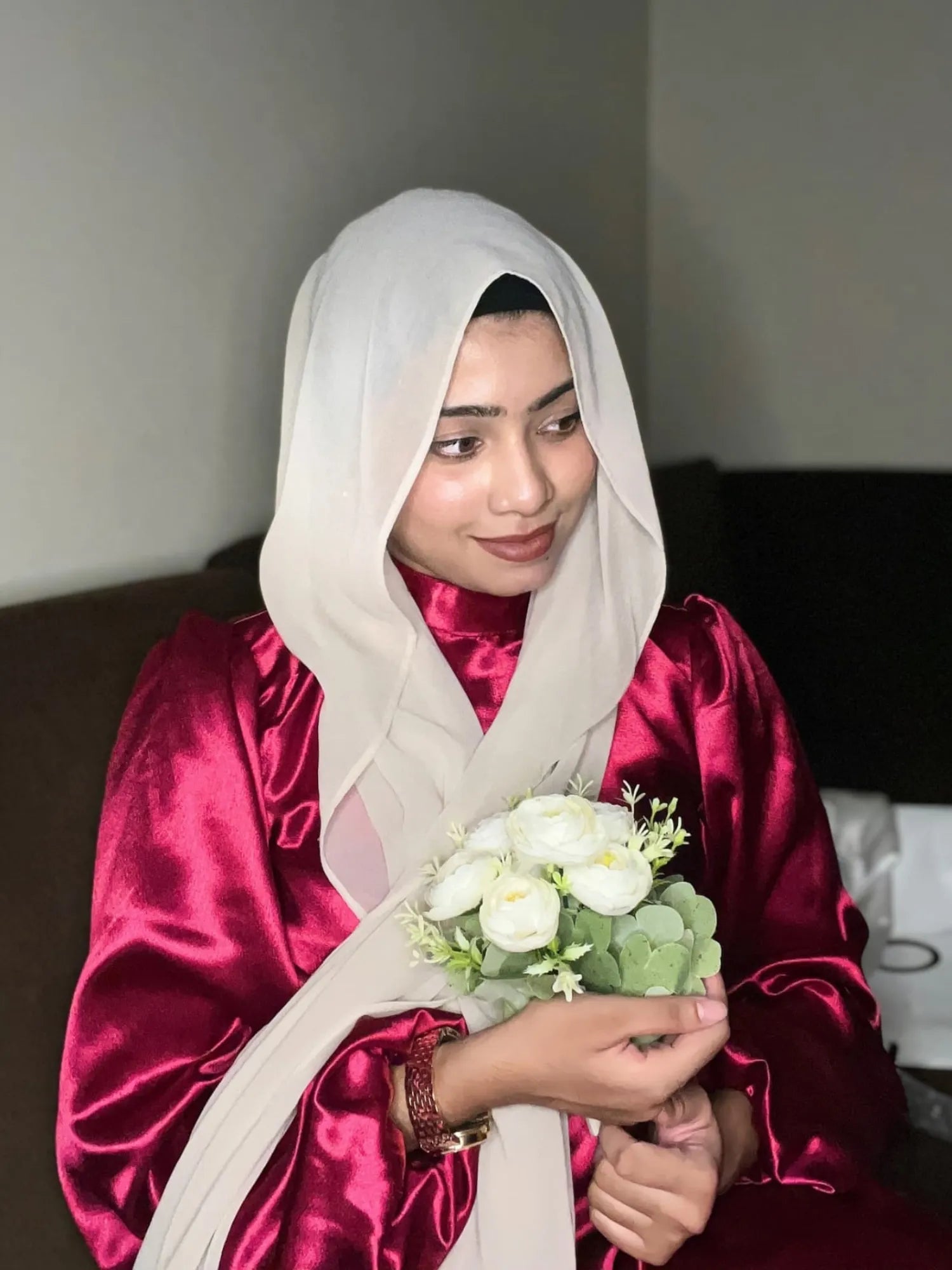 Model wearing a modest rosewood maxi dress, holding a bouquet of white flowers with elegant styling
