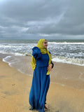 Yezwe modest wear dresses featuring a blue maxi dress and yellow hijab on a beach with ocean waves