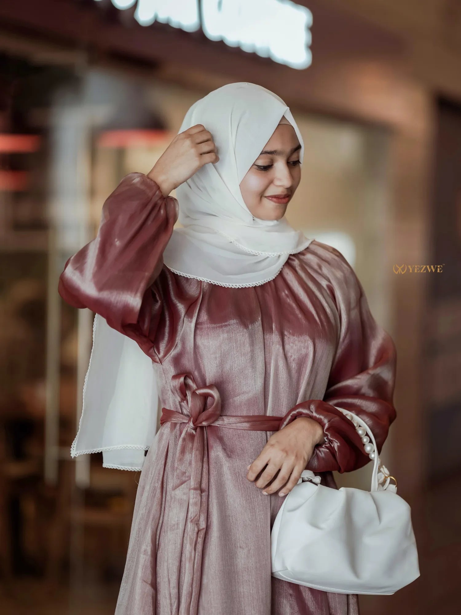 Elegant Yezwe modest wear maxi dress in soft tones, paired with a stylish handbag and hijab