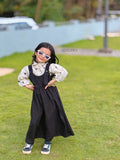 YEZWE junior girls Pinafore Dress black pinafore layered over printed blouse styled with white sunglasses and sneakers