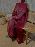 Yezwe satin top with net skirt in deep burgundy worn by woman sitting on wooden bench