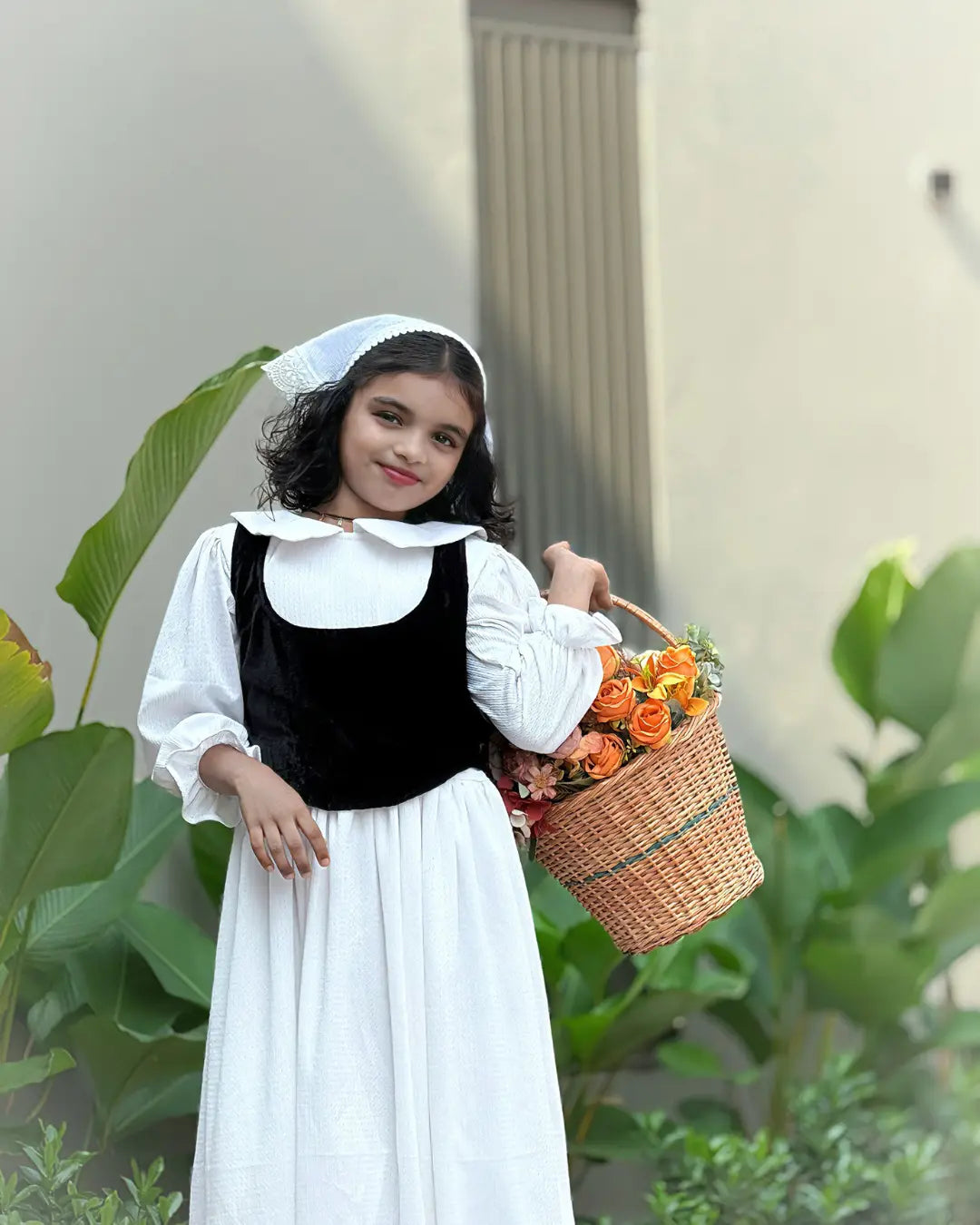 Junior girls wearing Yezwe Vintage Black Bodice Classic White Flared Maxi Dress, holding a flower basket in a garden