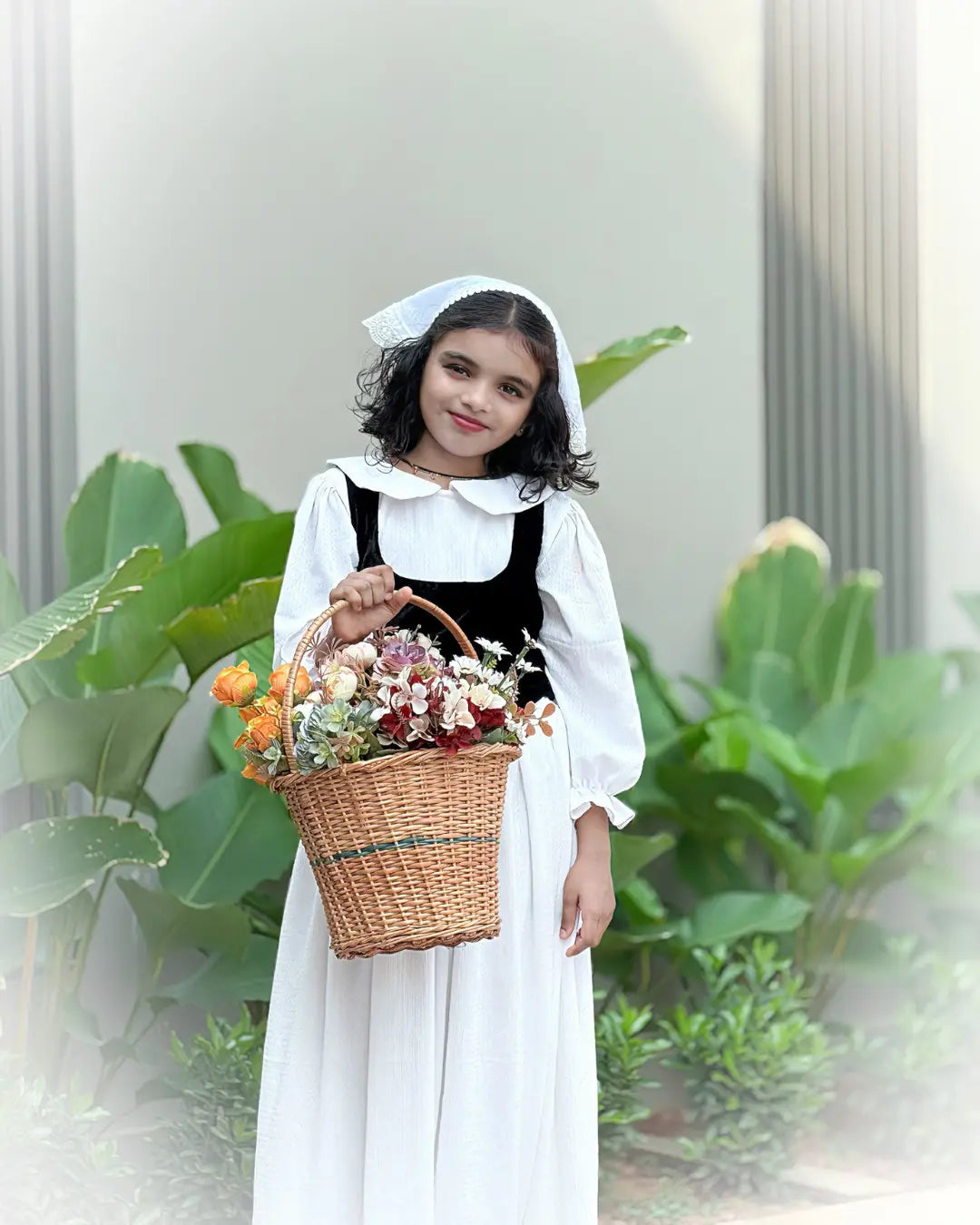 Junior girl wearing Yezwe Vintage Black Bodice Classic White Flared Maxi Dress holding a floral basket
