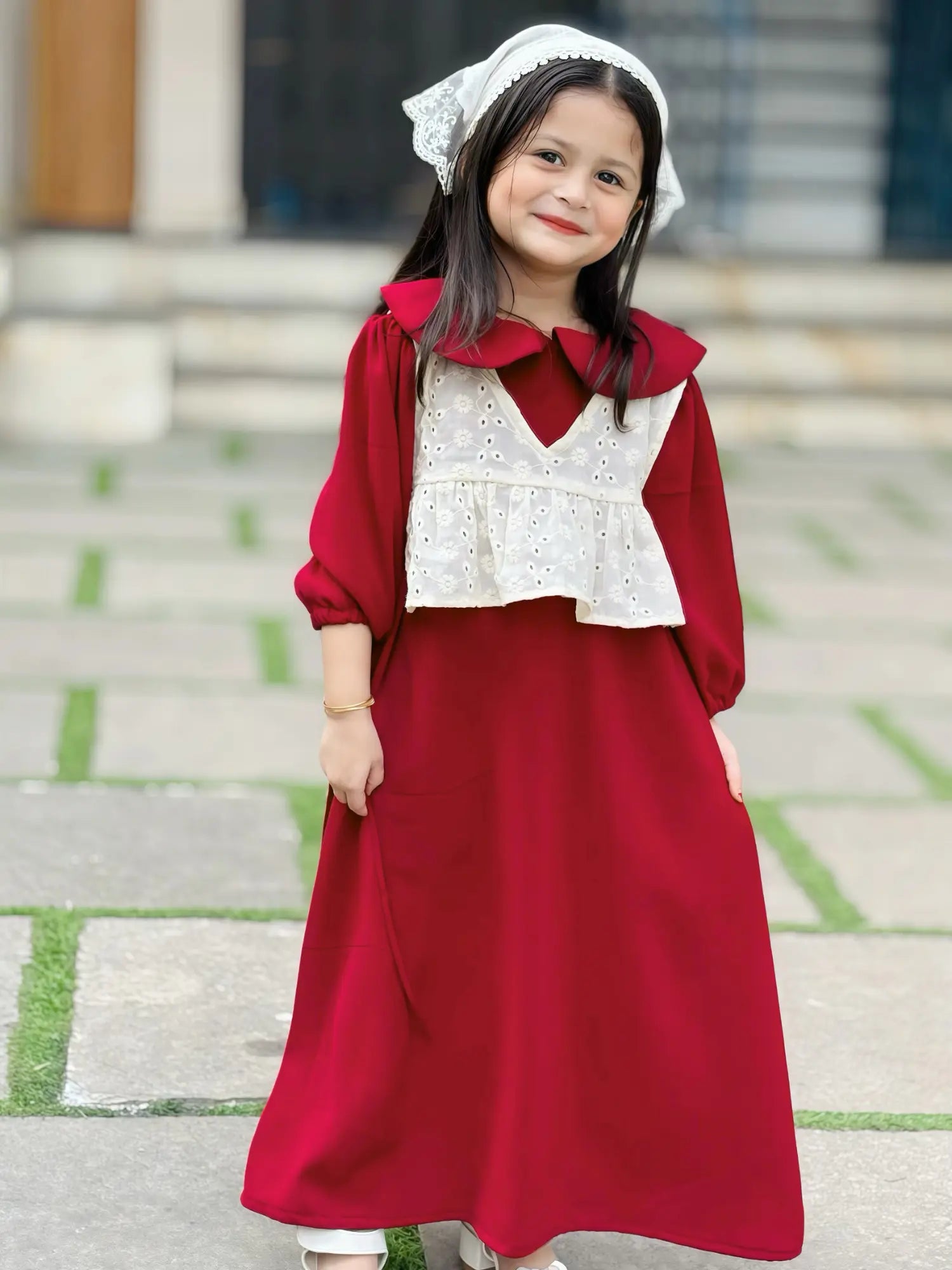 young girl wearing wine maroon modest maxi dress with a cream layered sleeveless top standing outdoors front view