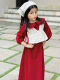 young girl wearing wine maroon modest maxi dress with a cream layered top posing playfully with hands on waist outdoors