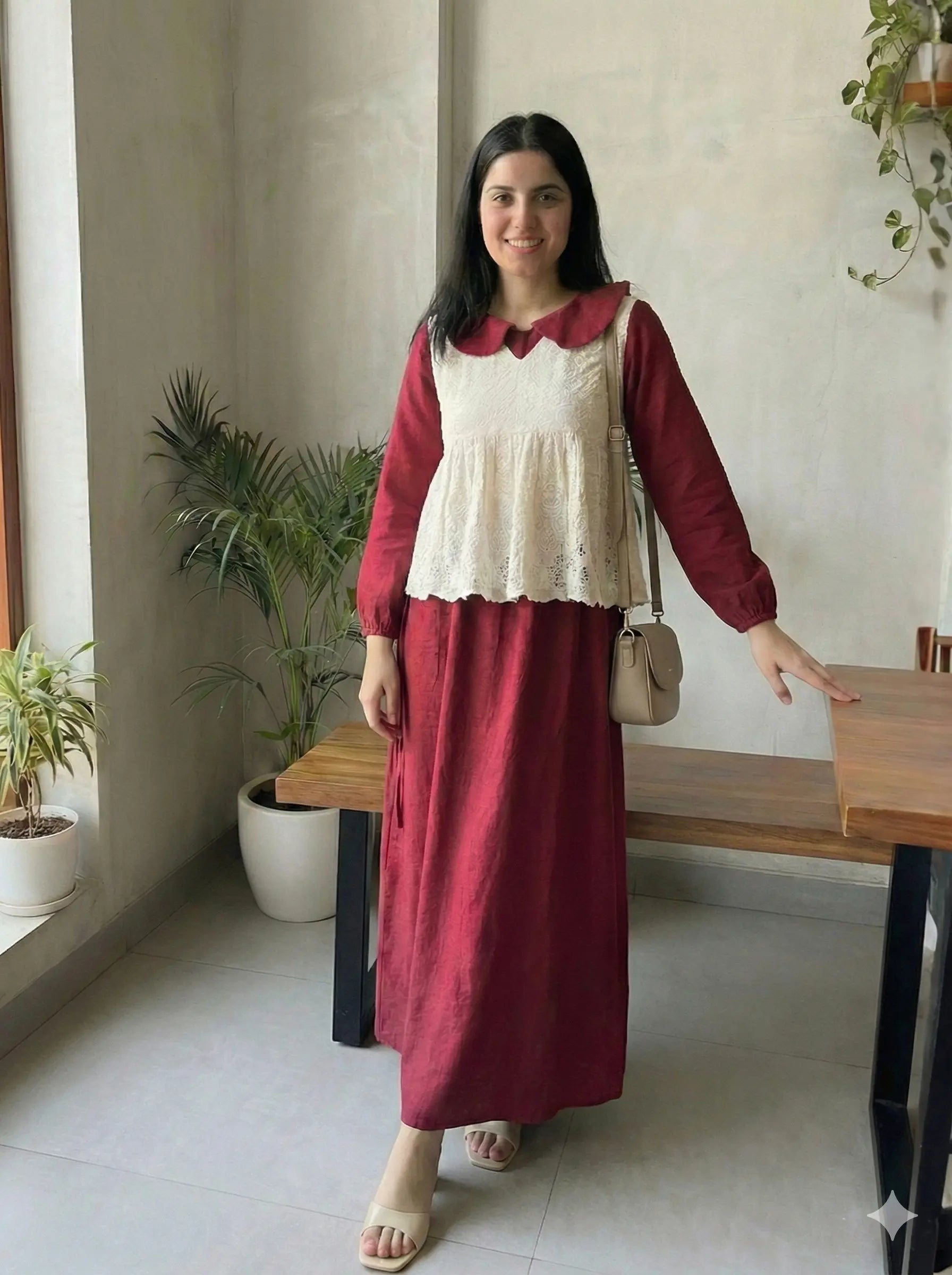 woman wearing wine maroon modest maxi dress with a cream layered sleeveless top walking indoors in a casual lifestyle setting